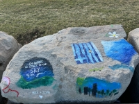 I'm naming the stars in the sky after you, Alex + Soph, flag, flowers and scenes. Chicago lakefront stone paintings, between Belmont and Diversey Harbors. 2024