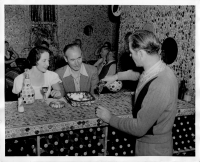 Vintage press photo: MIAMI, FLA: DEC-00-1940: The patience of Job, the friendliness of hundreds of delivery truck drivers as collectors and contributors has enabled Joe Wiser and his wife to build “Bottle Cap Inn” a bar in Miami at 1290 N. 119th St., whose walls and ceilings are decorated with over a million bottle caps. It took three years, a ton of nails and a ton of cement to do the job. Bottle caps are everywhere, on the floor, ceiling, bar, clock, lights, chairs, cash register, curtains, and even on the driveway. It’s the most unique rendezvous in Florida. Caps have been sent by admirers from the four corners of the world. Bottle tops, over the bar, and under it too, in the table tops, the ceiling and everywhere. Here’s the proud proprietor serving his guest. This photo gratis for the City of Miami. Miami New Service, Hamilton Wright Jr., Executive Editor.