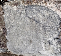 Hands hold tablet or book with star and indecipherable writing. Chicago lakefront stone carvings, Calumet Park. 2019