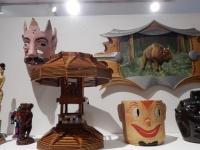 Top shelf center from Chicago We Own It: Mask,  Popsicle  stick lamp, Bruno Sowa buffalo relief,  happy face cookie jar