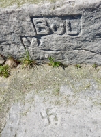 Swastika, level 2, with Bul, vertical. The swastika has been erased. Chicago lakefront stone carvings, between Foster Avenue and Montrose. 2018