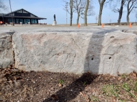 Triangle-bodied figure and face, with Theater on the Lake in the background. Chicago lakefront stone carvings at Fullerton. 2019