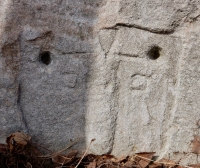 Cryptic carving next to triangle=bodied figure. Chicago lakefront stone carvings at Fullerton. 2019