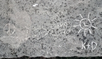 Peace symbol, heart, kissing fish, JC, PL, box, EB, crab, fish, LVR, L in a sun, K+D. Some of the carvings made at the June 20, 2026, DIY carving workshop. Chicago lakefront stone carvings, Promontory Point. 2026