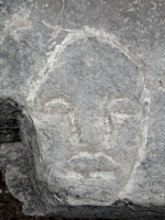 RT, face (detail), HP, TH in triangle. Made at the June 20, 2026, DIY carving workshop on the "Free Palestine" rock. Chicago lakefront stone carvings, Promontory Point. 2026