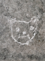 Cat face (detail), monstrous face, smiley sun. Made at the June 20, 2026, DIY carving workshop. Chicago lakefront stone carvings, Promontory Point. 2026
